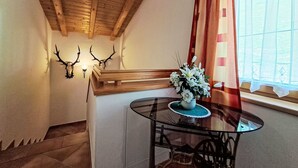 Una stanza con soffitto in legno, un tavolo in vetro con un vaso di fiori e una finestra con tende.