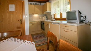 A compact kitchen with wooden cabinets, a microwave, a sink, and a television on the counter. - Schusterhäusl by Interhome (Mayrhofen)