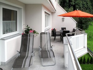 Relax on the balcony with two comfortable chairs and a small table, surrounded by lush greenery.