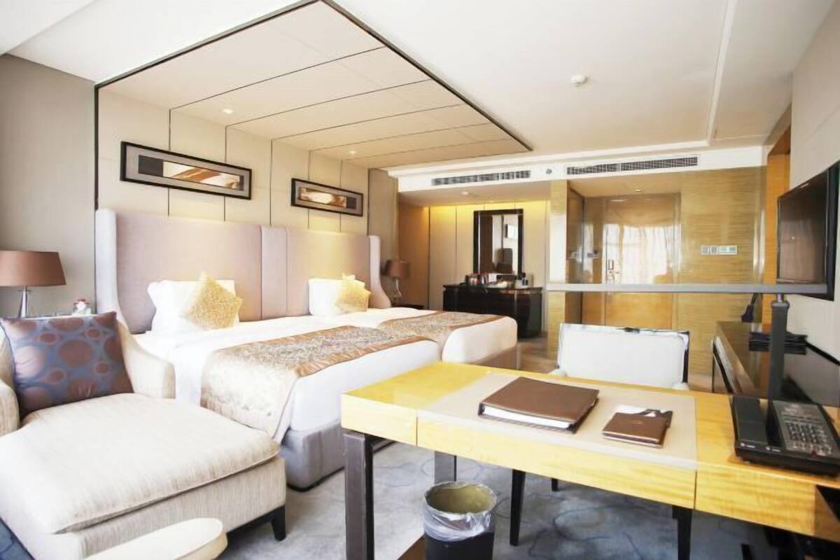 Ein Hotelzimmer mit zwei Betten, einem Schreibtisch, einem Sessel, einem Fernseher und einem Badezimmer.