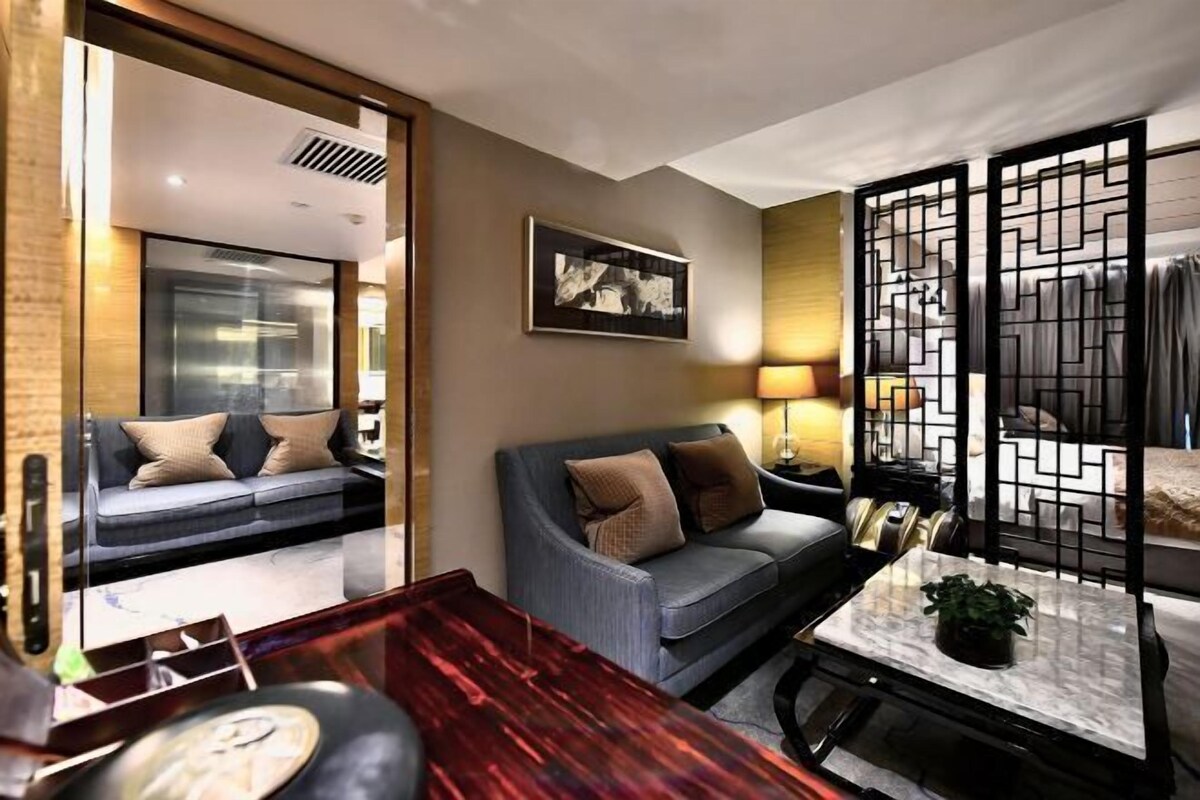 A modern living room with a sofa, a coffee table, and a decorative screen.