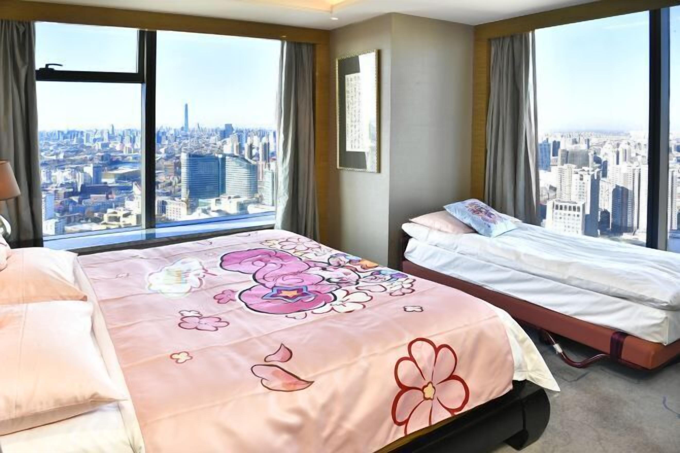 A hotel room with two beds, large windows with city views, and a framed picture on the wall.