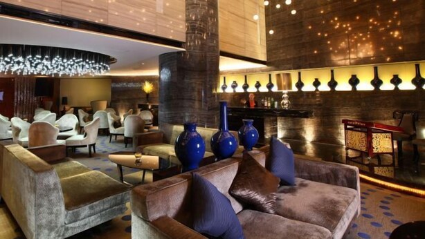 Eine moderne Lobby mit bequemen Sitzgelegenheiten, einer zentralen Säule und einer dekorativen Leuchte.