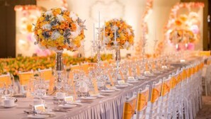 Una larga mesa de banquete dispuesta con sillas, centros de mesa y vajilla.