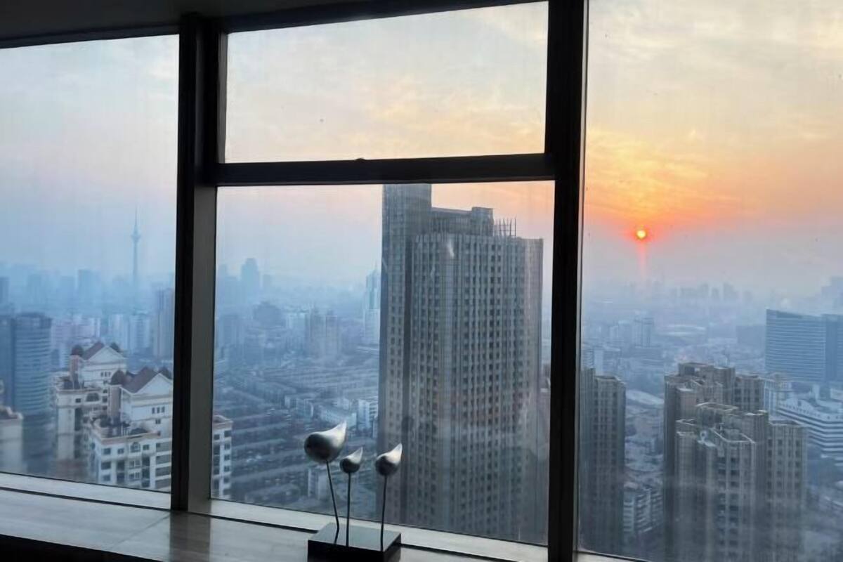 Blick durch ein großes Fenster auf eine Stadtlandschaft, einschließlich Wolkenkratzer und eines Turms.