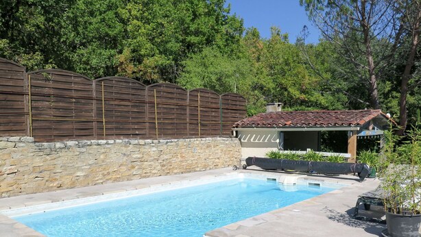 A swimming pool with stone walls and a wooden fence.