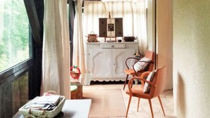 A cozy room with a stone-tiled floor, a white table with a basket, a wooden chair, and a white cabinet in the background.