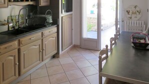 A kitchen with wooden cabinets, a black countertop, and a dining area with a table and chairs.