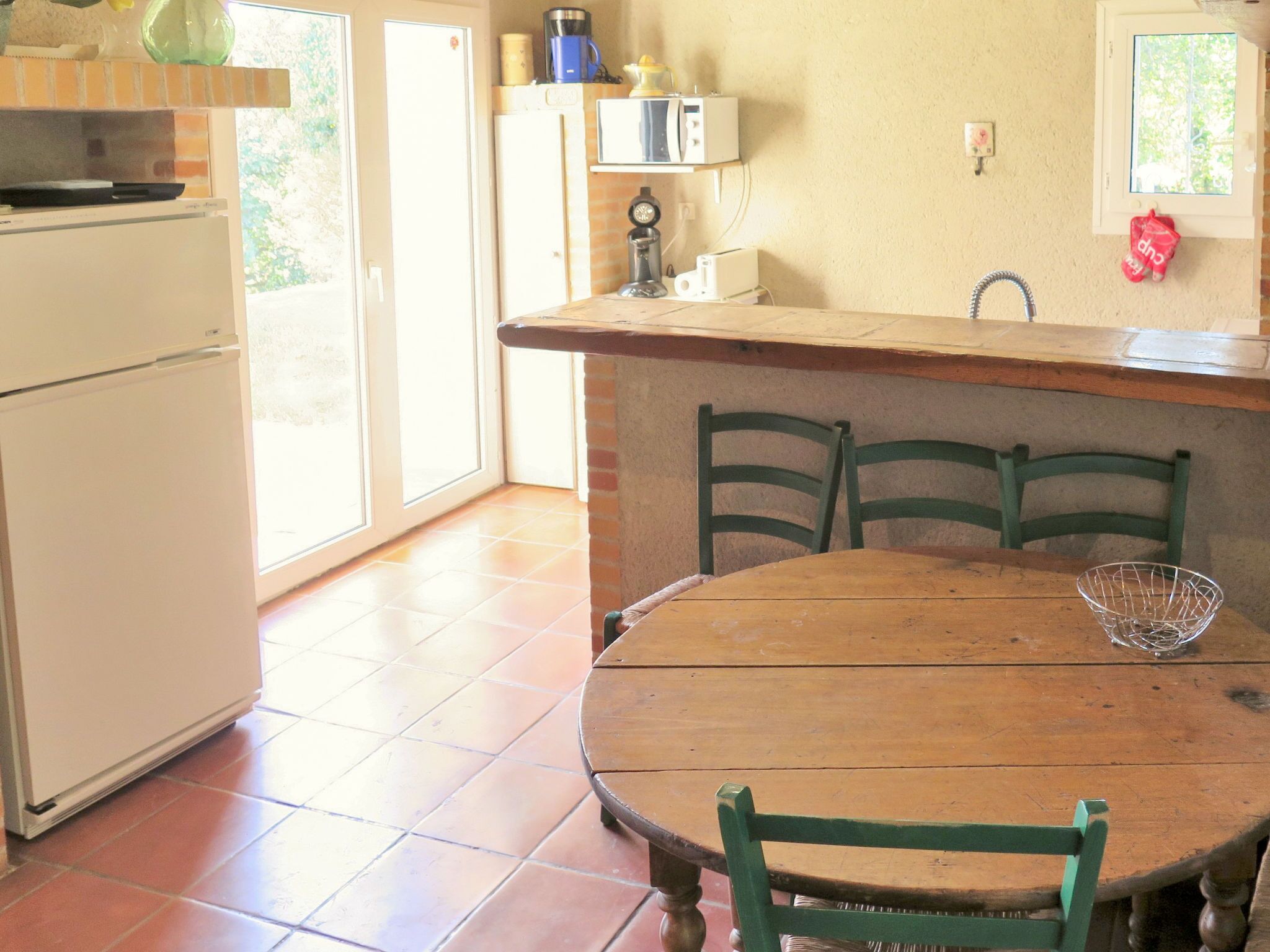 Une cuisine avec une table et des chaises en bois, un réfrigérateur, un évier et une fenêtre.