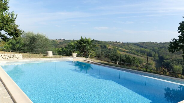 A rectangular swimming pool with clear blue water, surrounded by a stone deck and a metal fence. - Roque Piquet by Interhome (L'Honor-de-Cos)