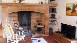 A living room with a brick fireplace, white furniture, a television, and a bookshelf. - Roque Piquet by Interhome (L'Honor-de-Cos)