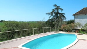 A rectangular swimming pool with a metal safety fence, surrounded by a gravel deck.