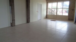 A spacious room with tiled flooring, a large sliding glass door, and a white door.