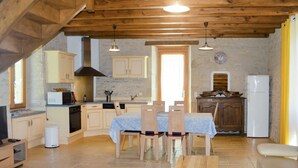 Una cocina rústica con vigas de madera, una mesa de comedor con sillas, un microondas, un fregadero y un refrigerador.