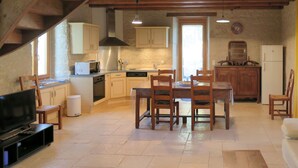 Una cocina amplia con armarios de madera, una mesa de comedor con sillas, un televisor y una pequeña mesa.