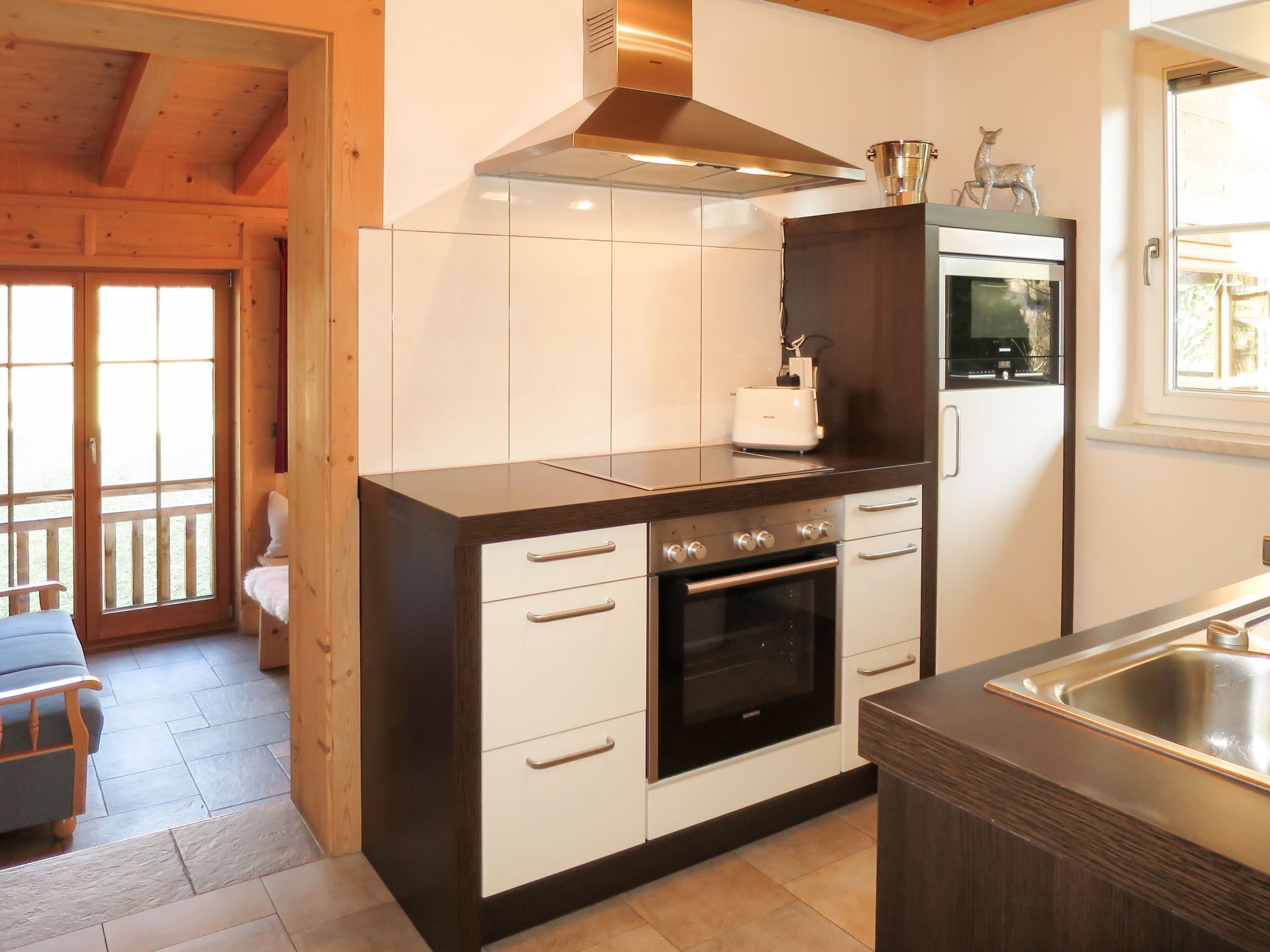 A compact kitchen with a built-in oven, a toaster, and a stainless steel sink.