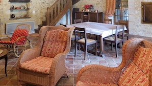 Un comedor rústico con muebles de mimbre, una escalera de madera y paredes de piedra.