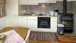 A compact kitchen with a stove, coffee maker, and a small trash bin. - Brugger by Interhome (Mayrhofen)