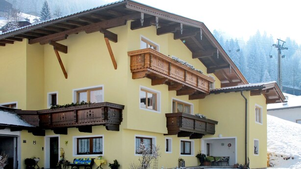 A yellow building with wooden balconies and a ski lift in the background. - Brugger by Interhome (Mayrhofen)