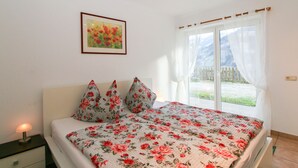 A bedroom with a bed, a nightstand, a framed painting, and a window with curtains. - Apartment Bair by Interhome (Mayrhofen)