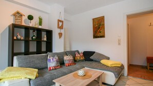 A living room with a grey sofa, a wooden coffee table, and a bookshelf. There are decorative pillows on the sofa and a small plant on the bookshelf. - Apartment Bair by Interhome (Mayrhofen)
