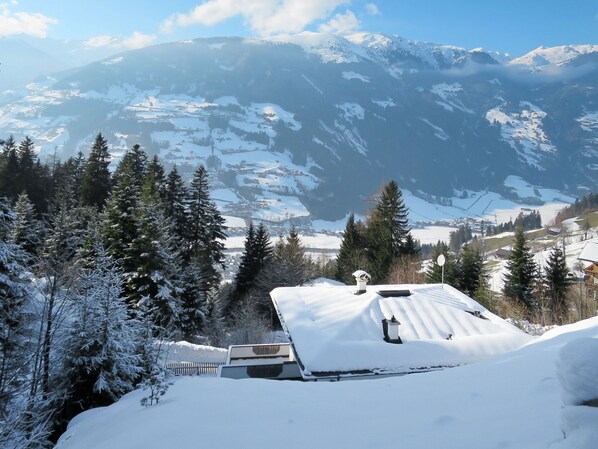A snow-covered mountain landscape with a house in the foreground.