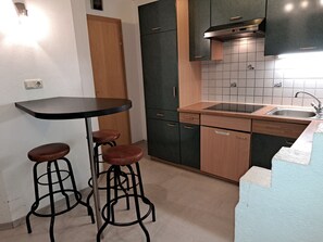Compact kitchen with a modern design, featuring a sink, stove, and wooden cabinets.