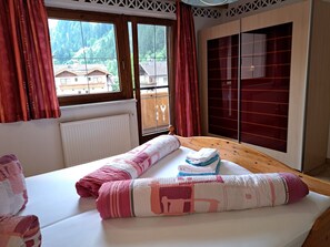 Relax in a spacious room with a large bed, wooden headboard, and a window offering a forest view.