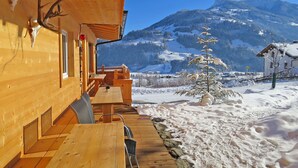 A wooden cabin with a wooden deck, a table, chairs, and a view of a snowy mountain landscape. - Talbach by Interhome (Mayrhofen)