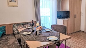 A hotel room with a dining table set for two, a sofa, a television, and a cabinet. - Apartment Rosa by Interhome (Mayrhofen)
