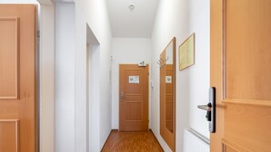 A hallway with wooden doors, white walls, and a wooden floor. - Apartment Rosa by Interhome (Mayrhofen)