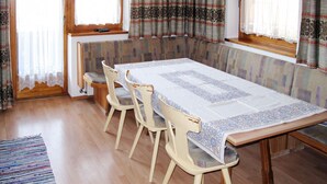 Un coin repas comprenant une table en bois, quatre chaises et un banc.