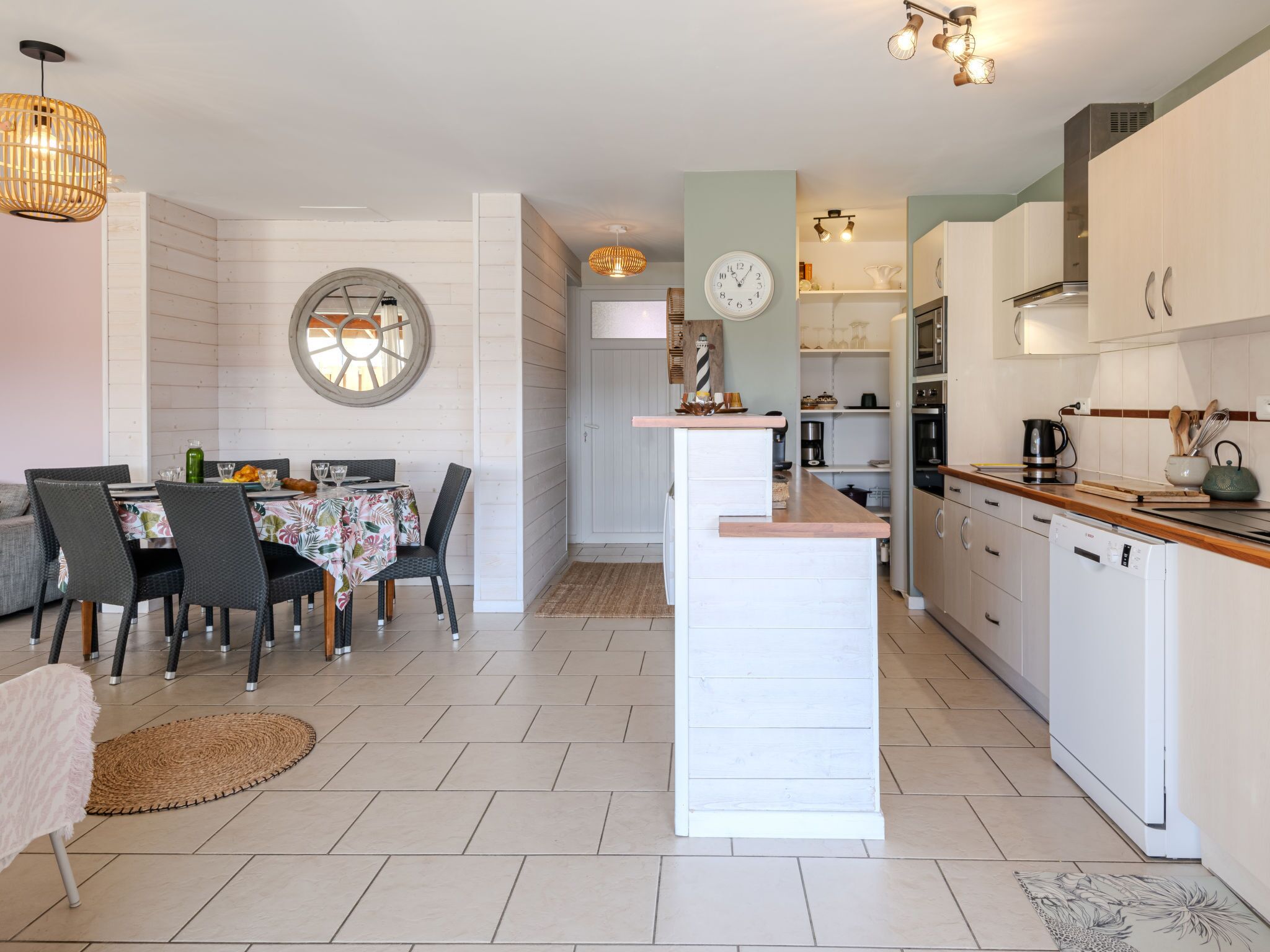 A modern kitchen with white cabinets, a central island, and a dining area with a round table and chairs.