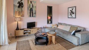 Una sala de estar con un sofá, una mesa de centro, un televisor y obras de arte en las paredes.