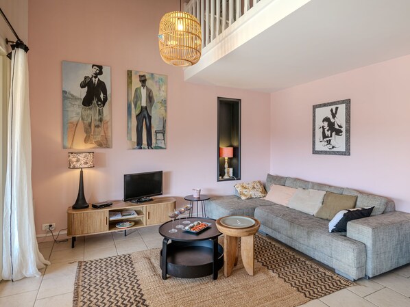 A living room with a sofa, a coffee table, a TV, and artwork on the walls.
