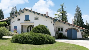 A two-story house with a white facade, blue shutters, and a tiled roof.