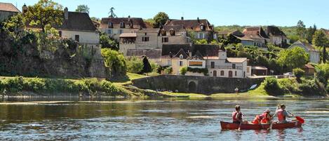 A river with houses on the banks, a bridge, and people kayaking.