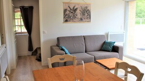 Un salon avec un canapé gris, une table en bois et un tableau accroché au mur.