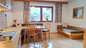 Een ruimtelijke leefruimte met een kitchenette, eethoek en zithoek.