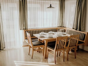 A dining area with a wooden table set for four, a bench with cushions, and a hanging light fixture.