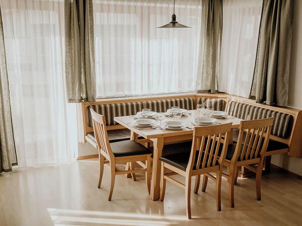 A dining area with a wooden table set for four, a bench with cushions, and a hanging light fixture.