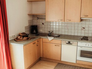 Una cocina compacta con armarios de madera, una cafetera, un fregadero y un lavavajillas.