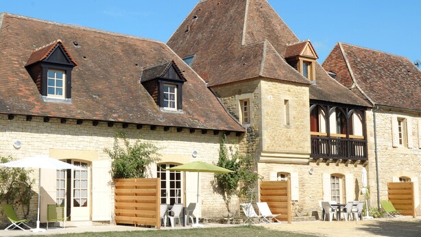 A traditional stone building with multiple pitched roofs and a wooden balcony.
