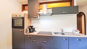 A compact kitchen with a built-in oven, a coffee maker, and a sink. - Gielerhof by Interhome (Zell am Ziller)