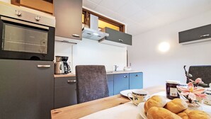A compact kitchen with a microwave, coffee maker, and a sink. There is a wooden table with bread and a cup. - Gielerhof by Interhome (Zell am Ziller)