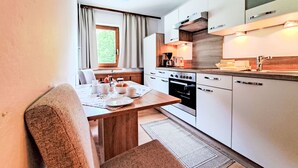 Une cuisine moderne avec un coin repas, comprenant une cuisinière, un four et une machine à café.