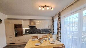 Cocina compacta con comedor, horno integrado y ventana con cortinas.