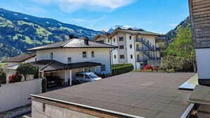Un edificio residencial con zona de estacionamiento techada, una escalera que conduce a un piso superior y vistas de un paisaje montañoso.