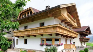 Ein traditionelles Chalet mit Holzbalkon, Steinuntergrund und einem gepflegten Garten.