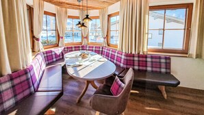 Une pièce chaleureuse avec une table ronde, des sièges à motifs écossais et de grandes fenêtres donnant sur l’extérieur.